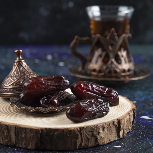 Hot tea behind of dry dates on blue background. High quality photo